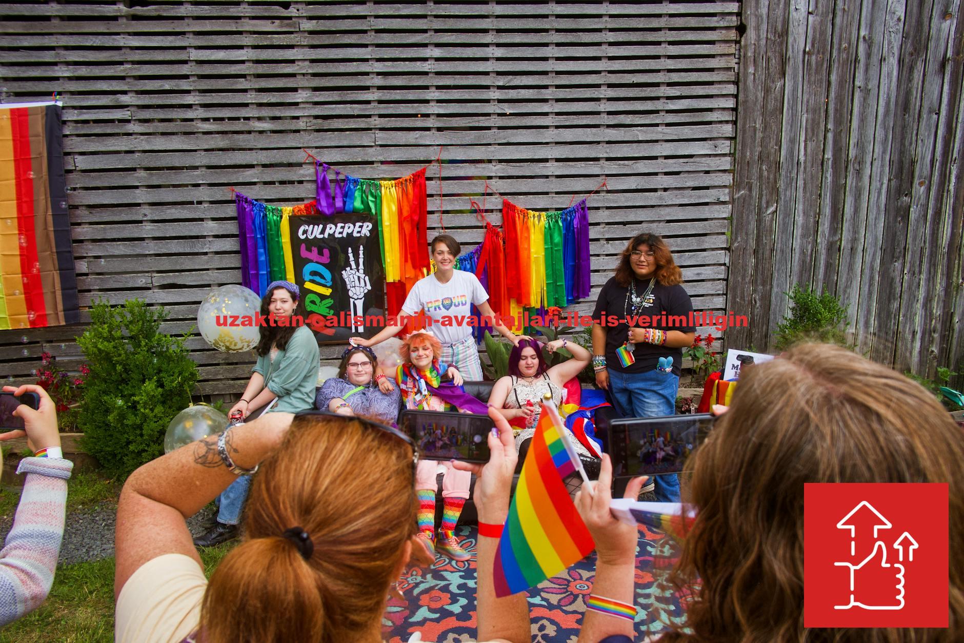 Group of diverse individuals celebrate Pride with colorful flags and joyful smiles outdoors.