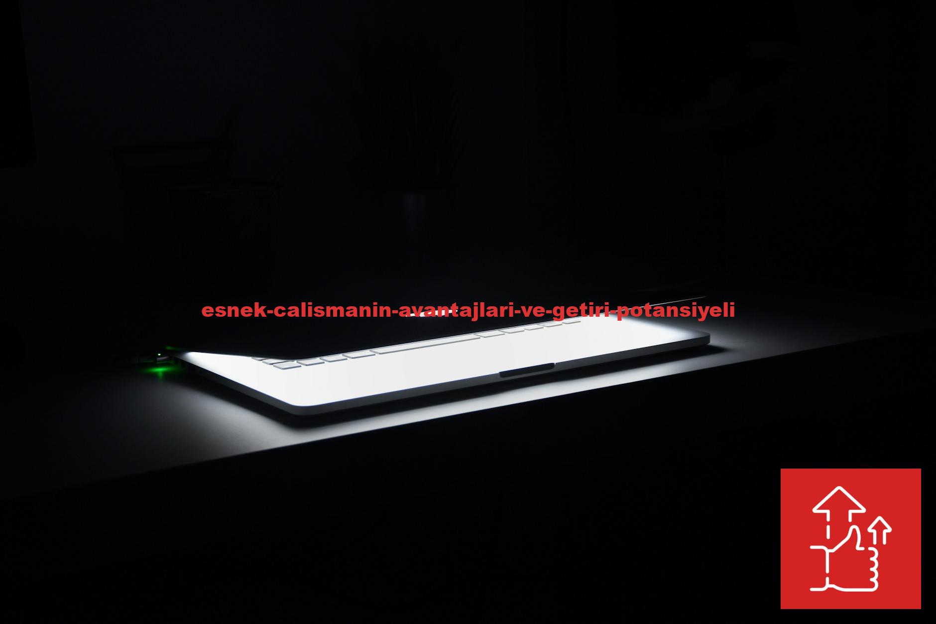A dramatic, low-light image of a slightly open laptop with glowing keys on a dark desk.