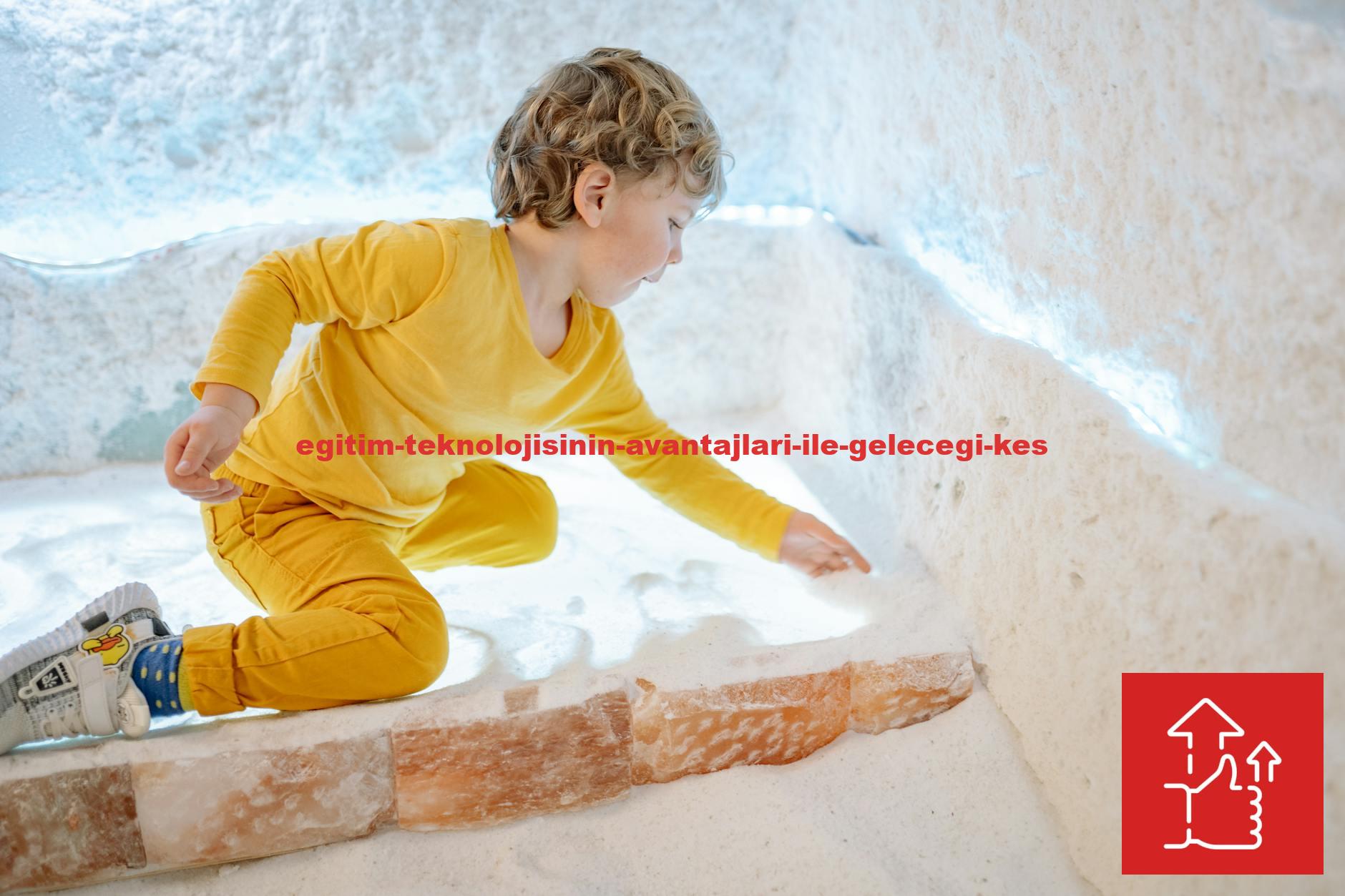 A young boy in a yellow outfit plays with salt in an illuminated indoor room.