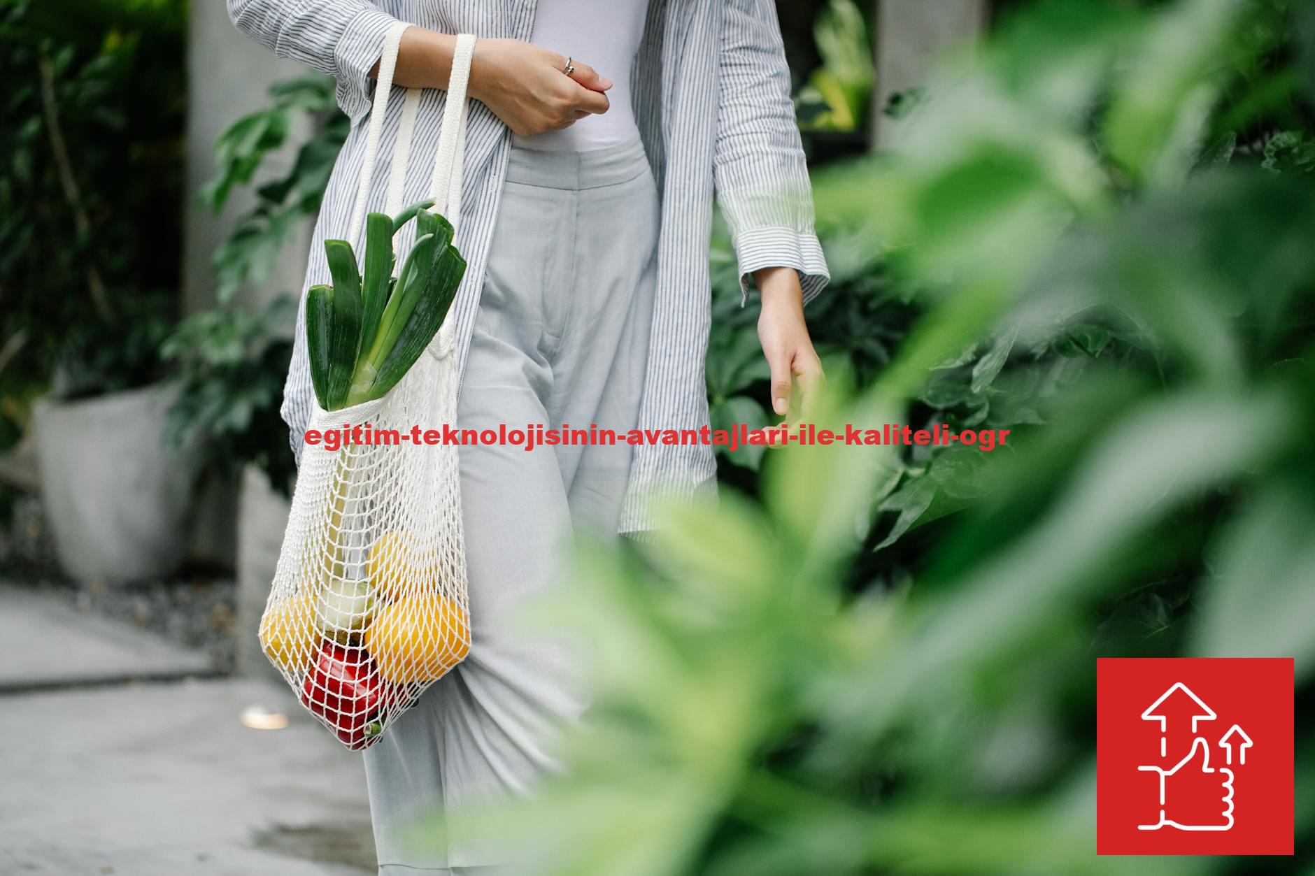 Crop anonymous female wearing casual outfit carrying net grocery bag with ripe vegetables including leek and capsicums in garden