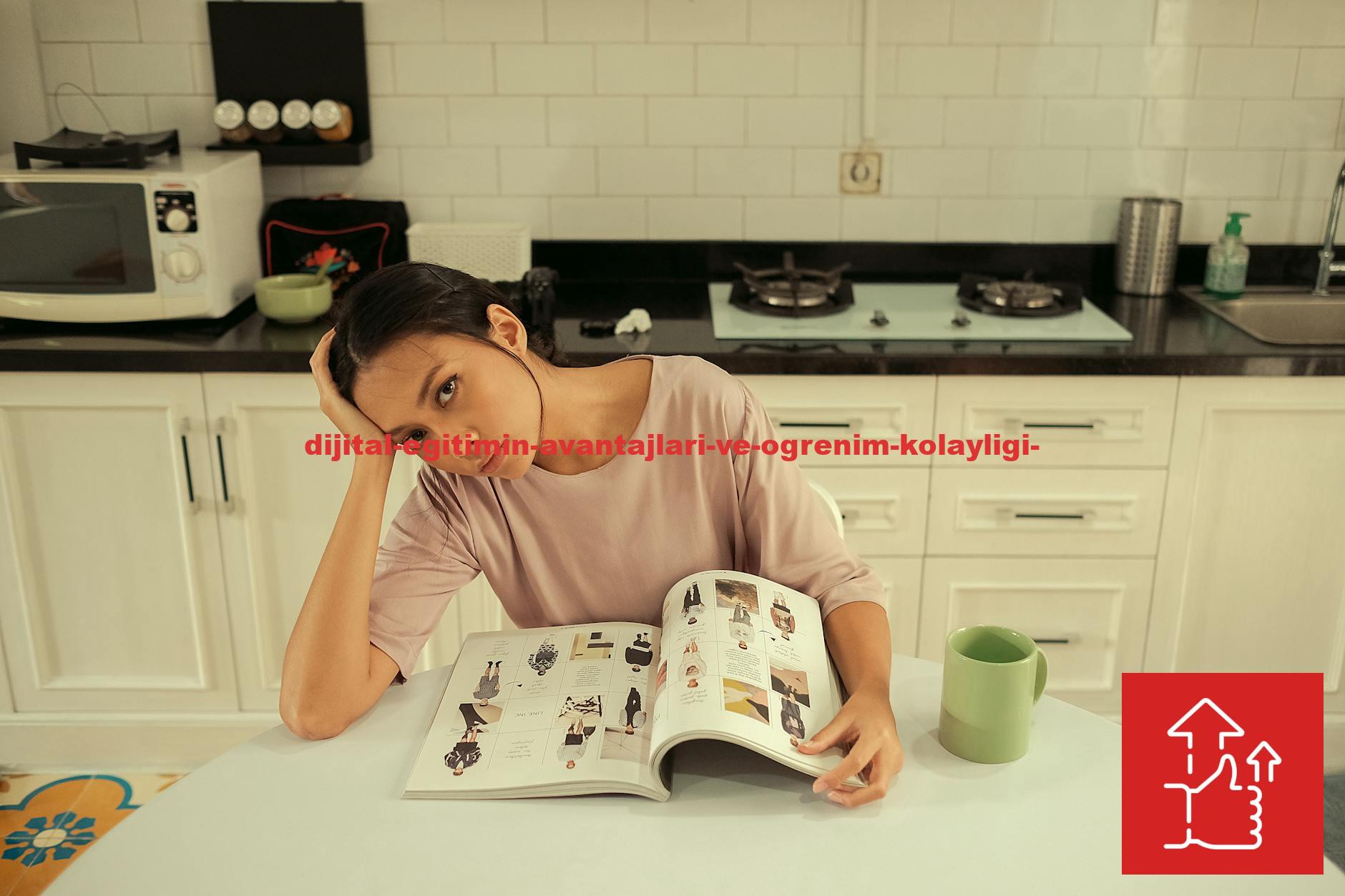 Woman sitting in a kitchen, reading a magazine at a table with a thoughtful expression.